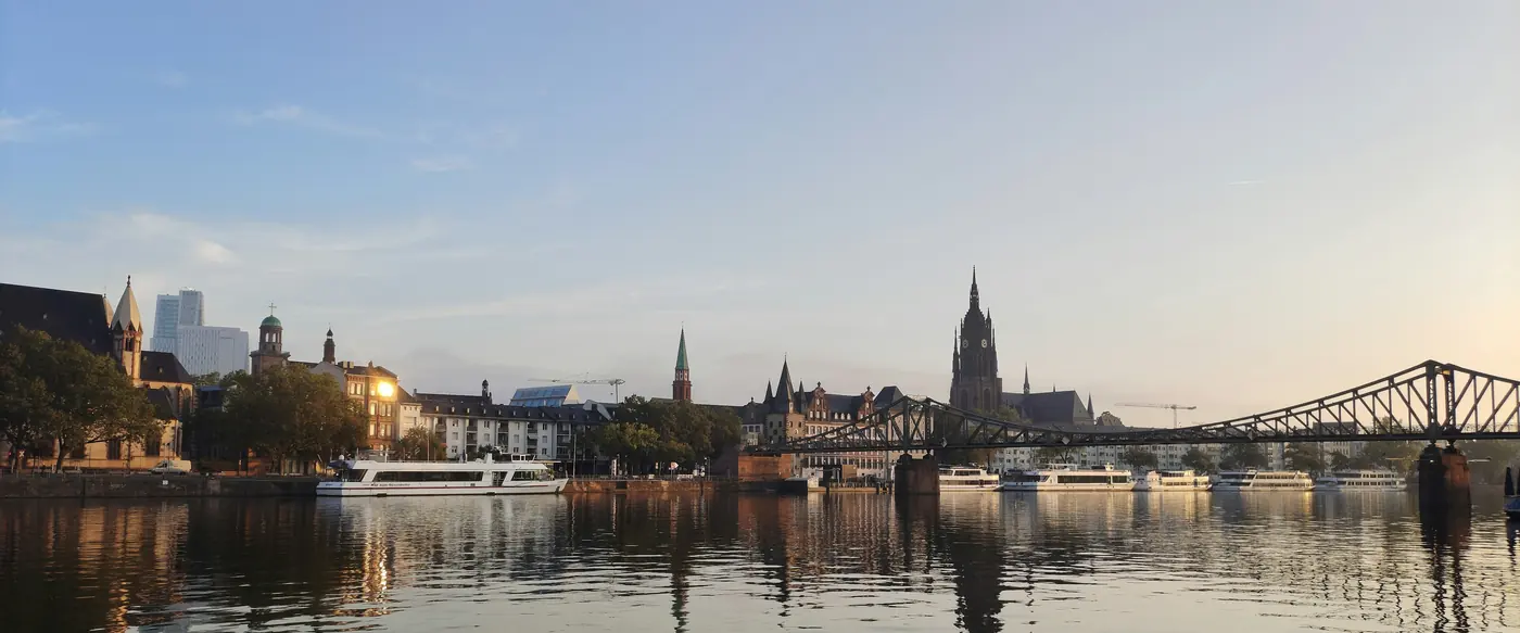 Flussufer mit einer Stadtsilhouette im Abendlicht